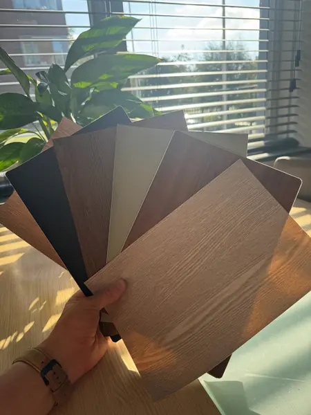 Een waaier kleursamples in de hand, van eiken en walnoot tot zwart en zandkleur